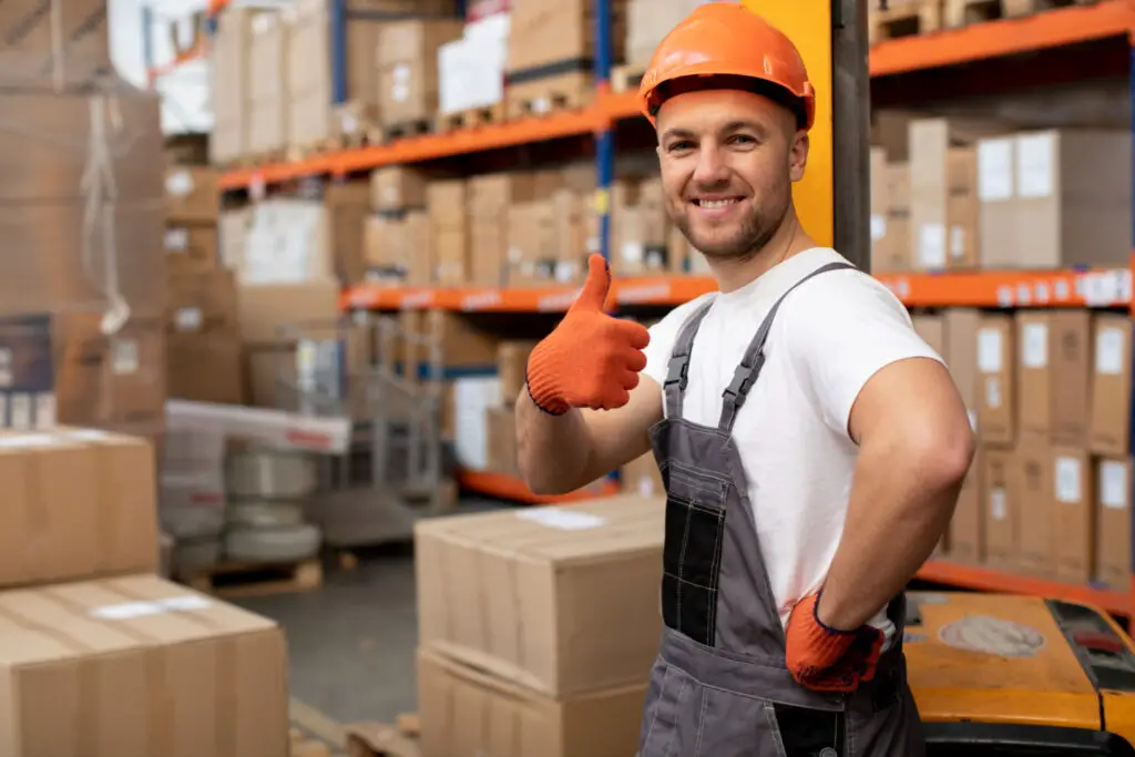A male college student smiling while organizing boxes as a part-time warehouse associate