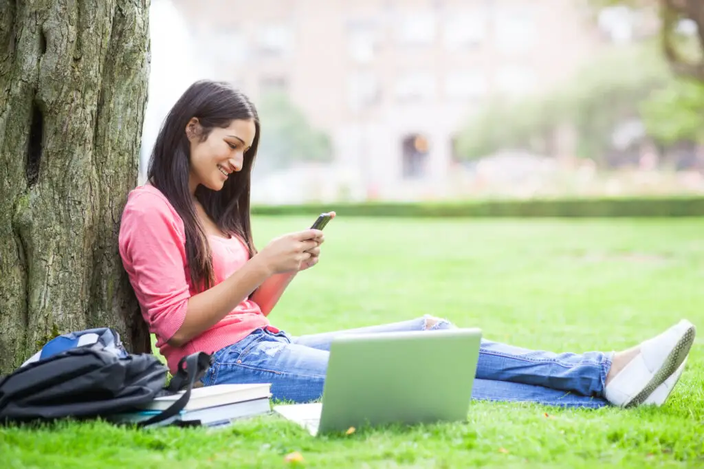 female-college-student-using-electronic-gadgets-from-her-college-packing-checklist-to-study-outdoors