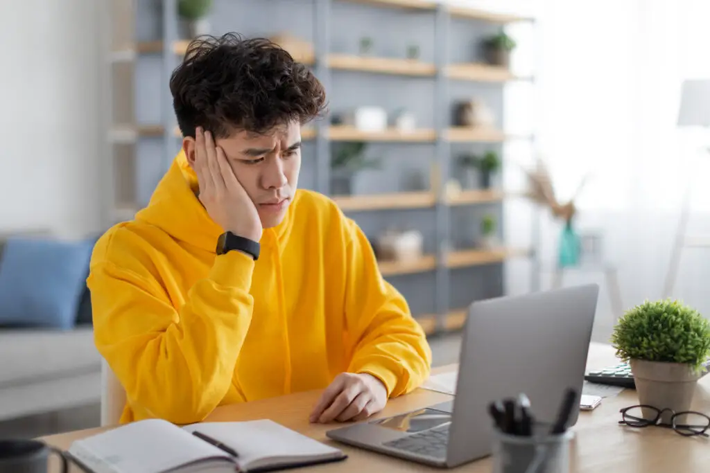 male-college-student-in-yellow-hoodie-diligently-double-checks-his-FAFSA-application-to-make-sure-his-name-date-and-signature-are-properly-signed