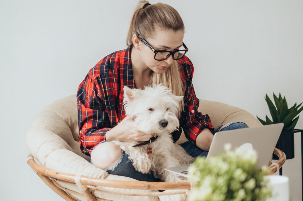 female-college-student-holding-a-puppy-and-a-laptop-on-her-lap-reviewing-her-college-packing-checklist