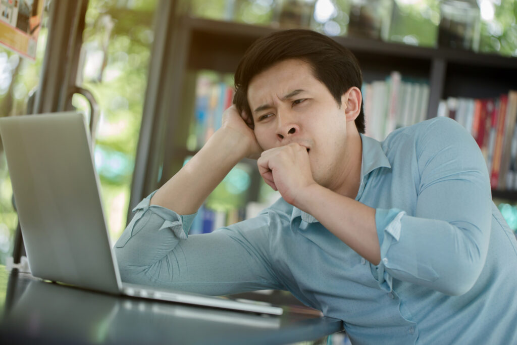 male-college-student-yawning-in-front-of-a-laptop-after-procrastinating-his-FAFSA-application-