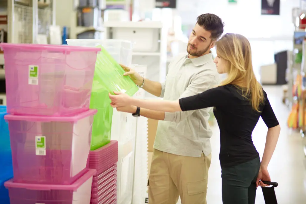 male-and-female-college-students-in-a-store-holding-storage-bins-to-buy-for-their-college-packing-checklist