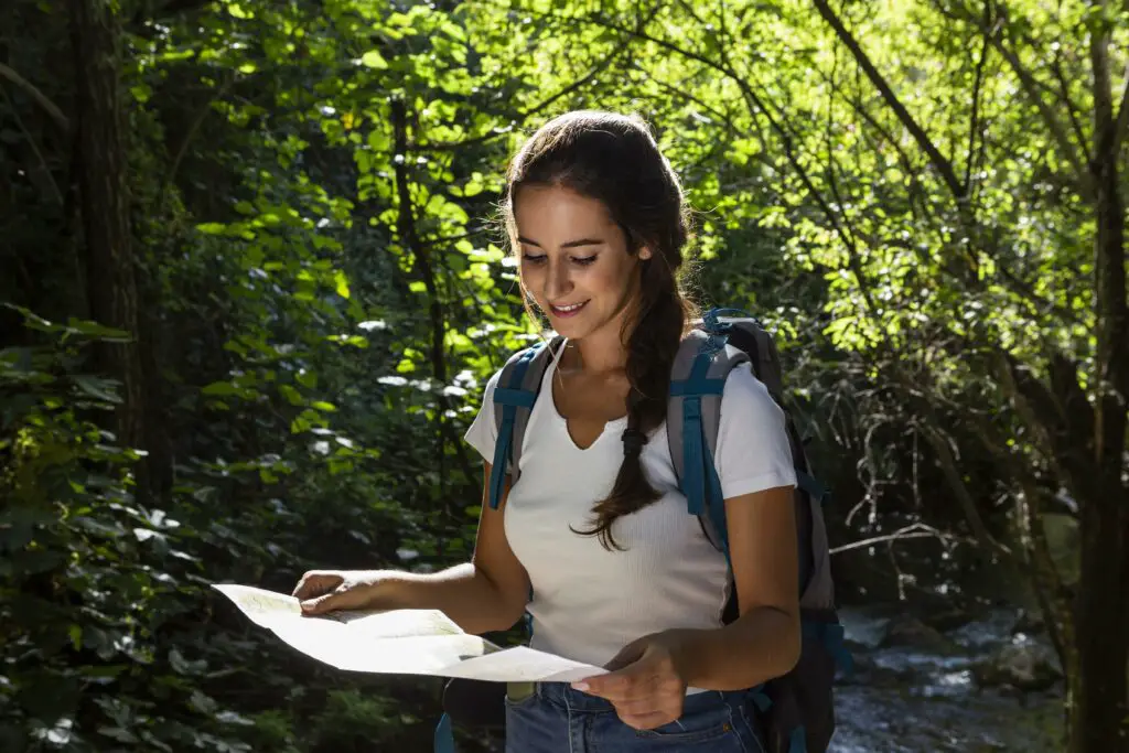 A smiling female forestry student checks her map to navigate the university research forest