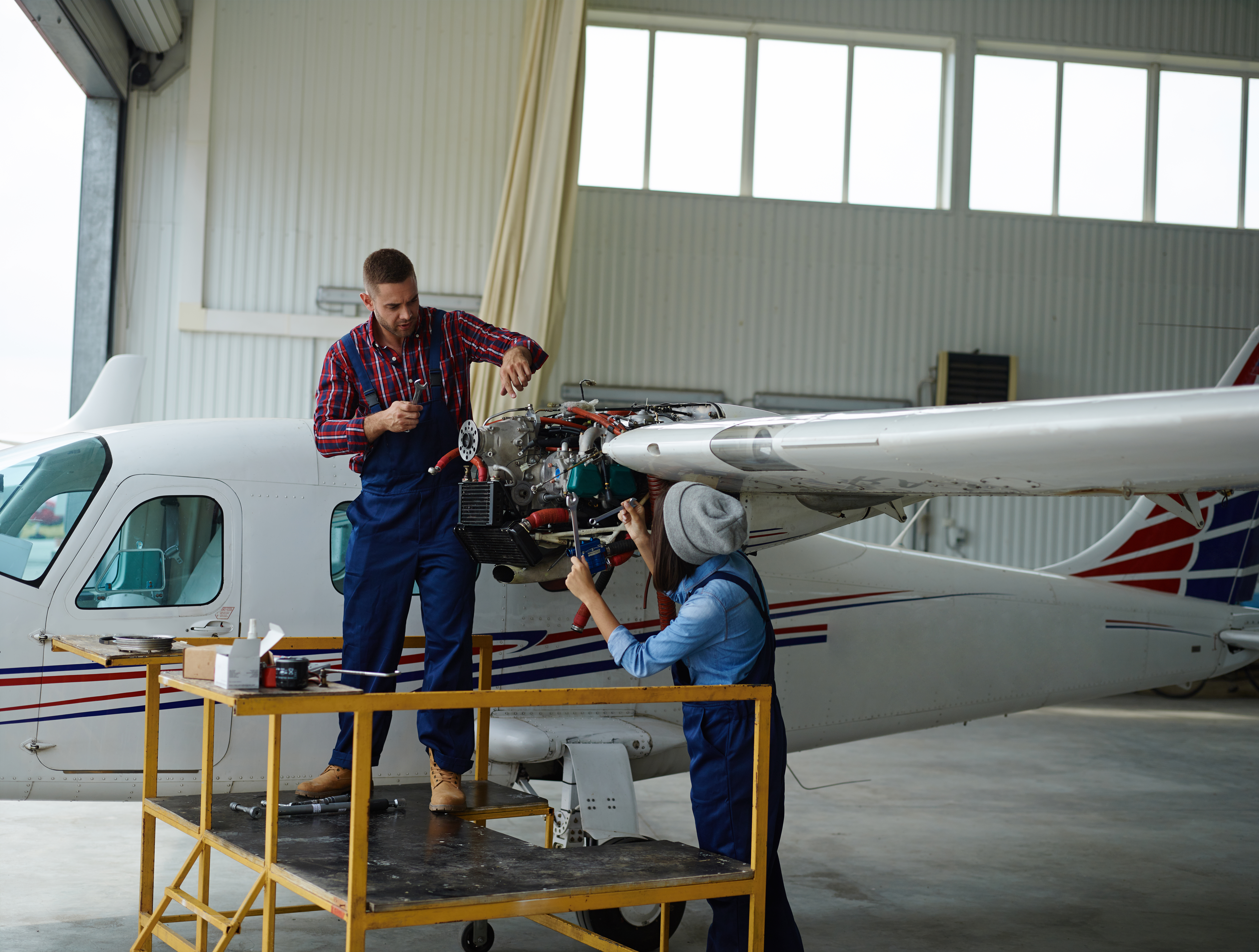 Male and female aeronautics students fixing plane wiring in an aircraft hangar found inside one of the best aeronautical colleges