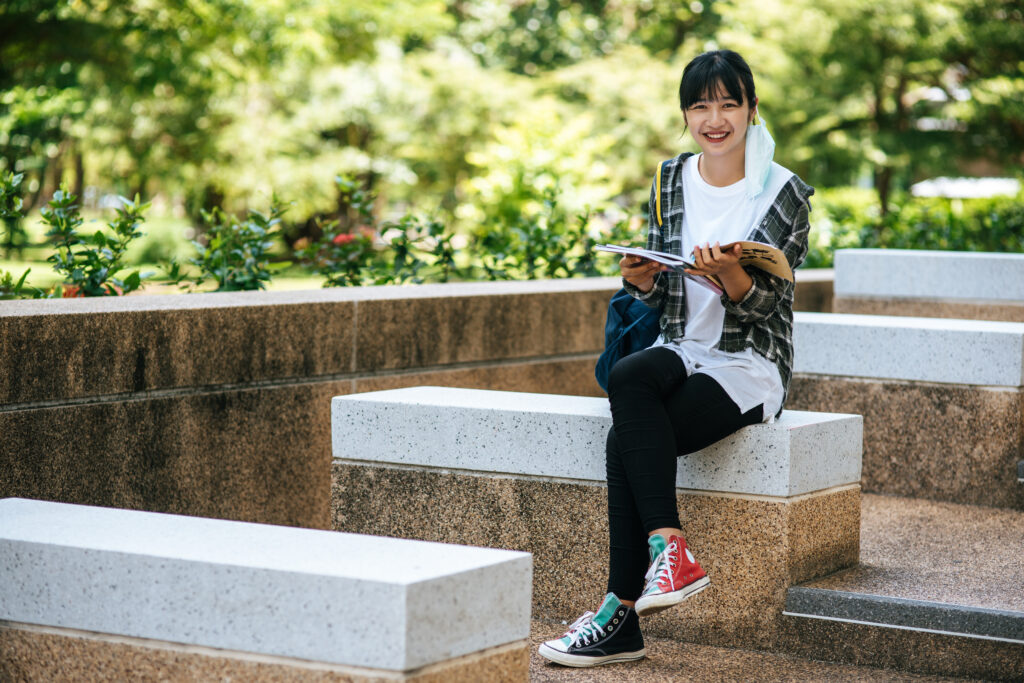 A Japanese student from Kindai University, one of the weirdest college names worldwide, smilng as she reads a book