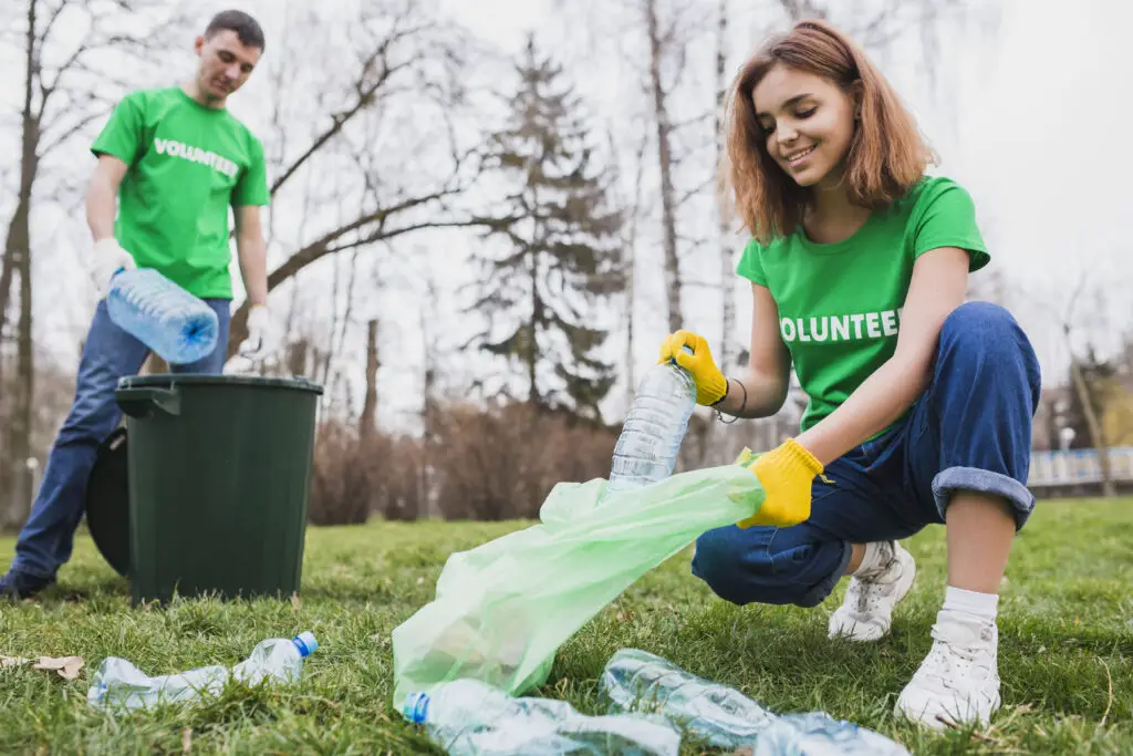 Two college volunteers picking up plastic trash in the park