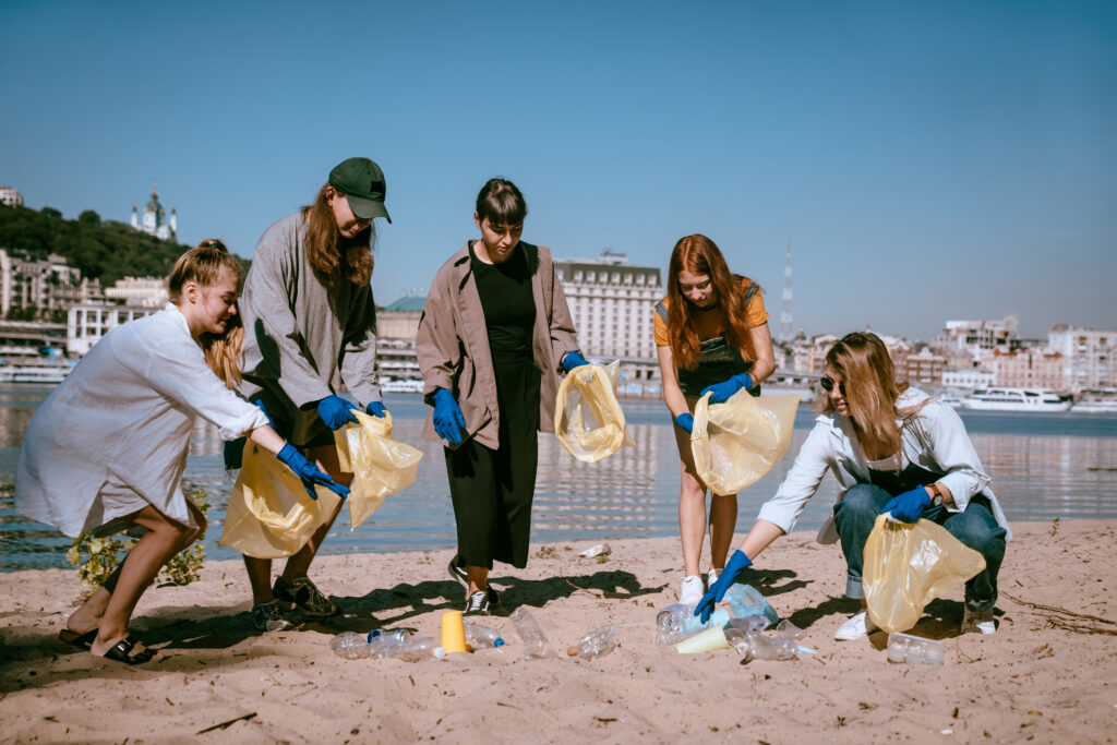 Female college students volunteering to pick up trash by the shore in their spare time