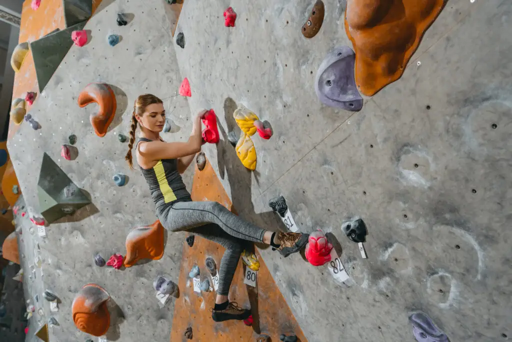 a female international college student wall climbing in the college's recreation area during her free time