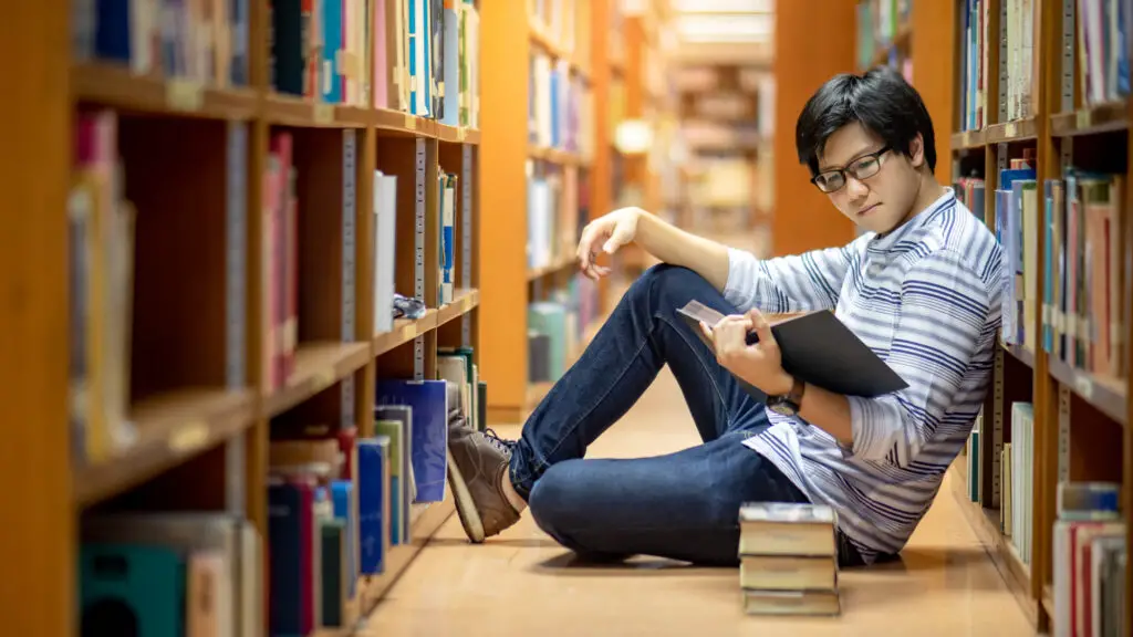 a-male-philosophy-major-in-a-library-reading-books-sitting-on-the-floor