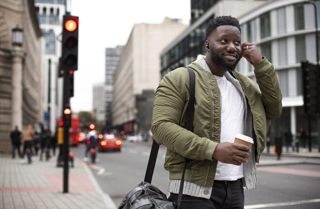 A male college student happily walking along the Boston downtown on the way to his free tour meeting place  
