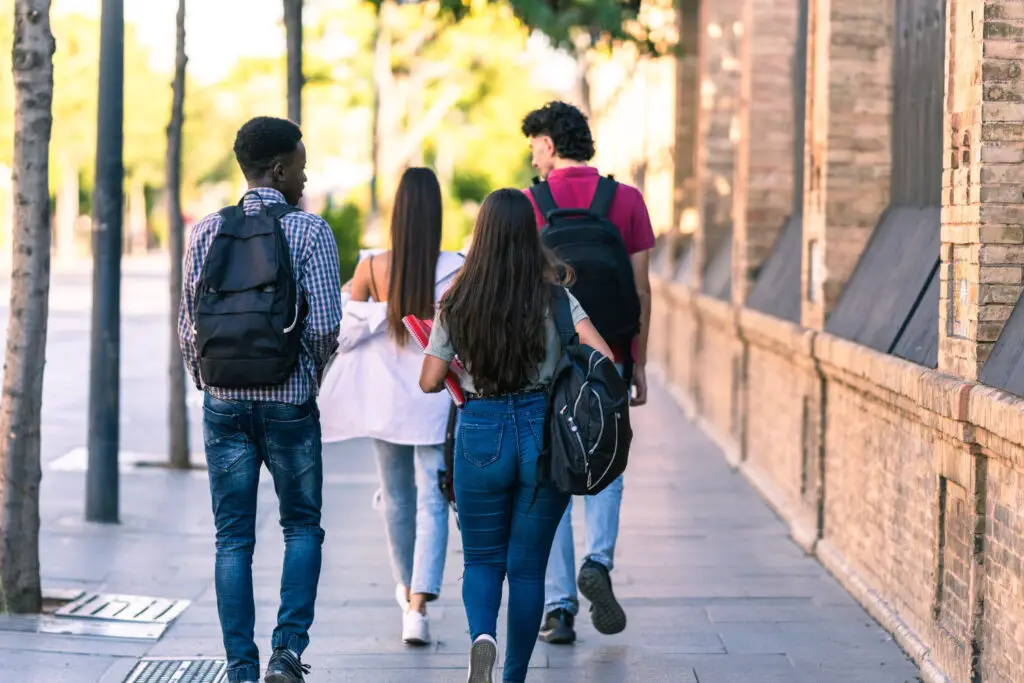 back-of-group-of-multi-racial-students-with-bags-walking-down-the-street
