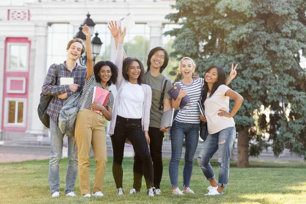 A happy group of college students from diverse nationalities hanging out on their outdoor school grounds 