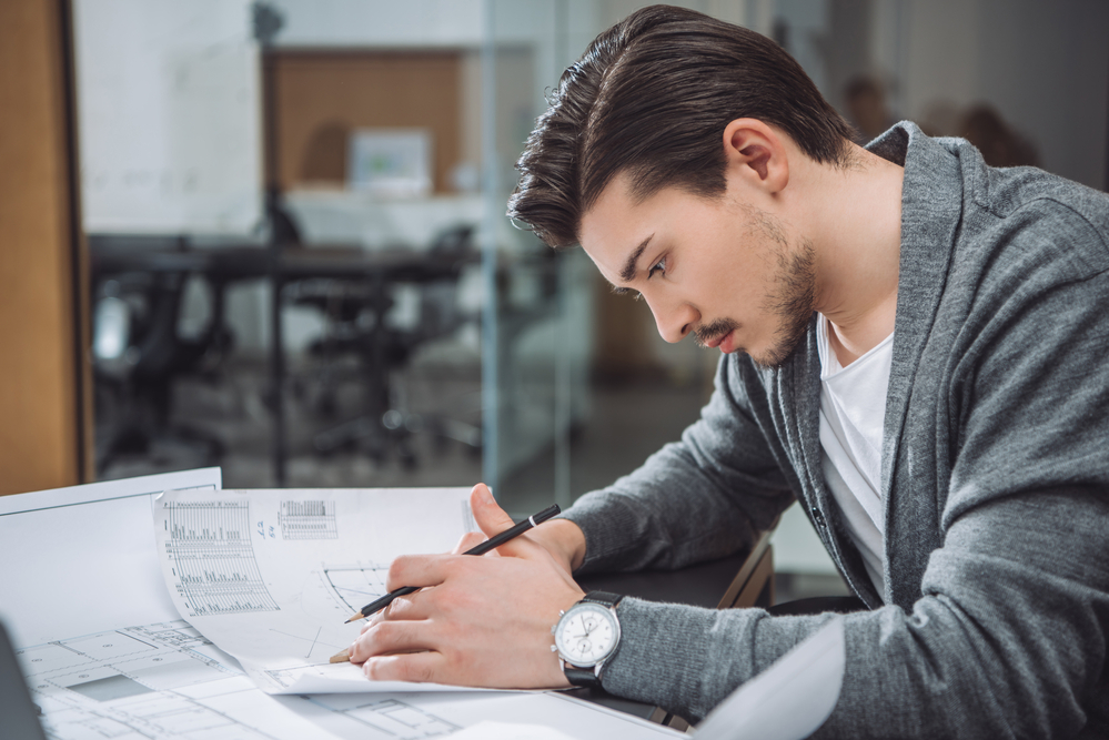 A well-groomed male architect focusing on his structural drawings