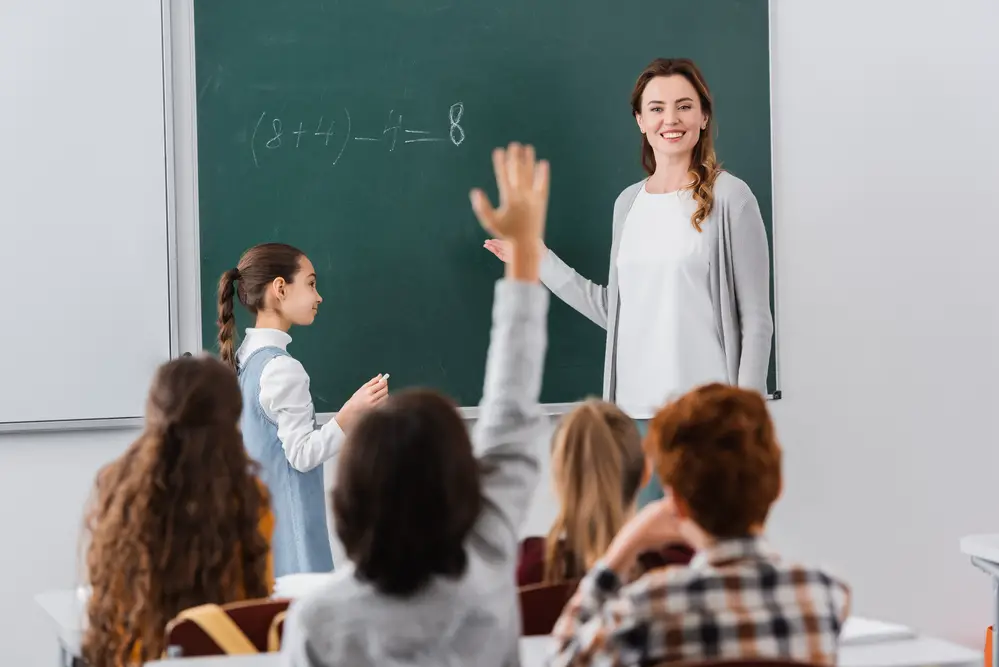 blonde-female-math-schoolteacher-teaching-a-group-of-children-in-classroom
