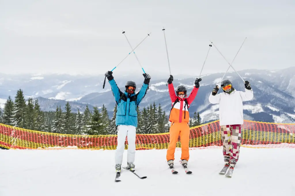 three college students having fun while skiing at a winter mountain ski resort