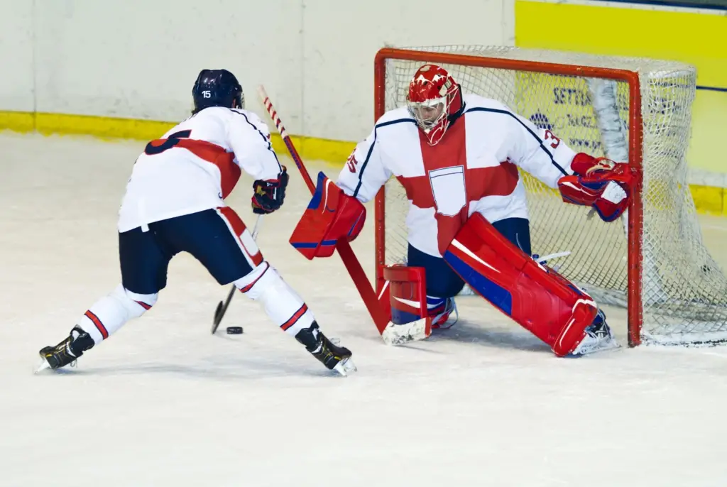 college students wearing red blue and white uniform playing ice hockey in a skating rink