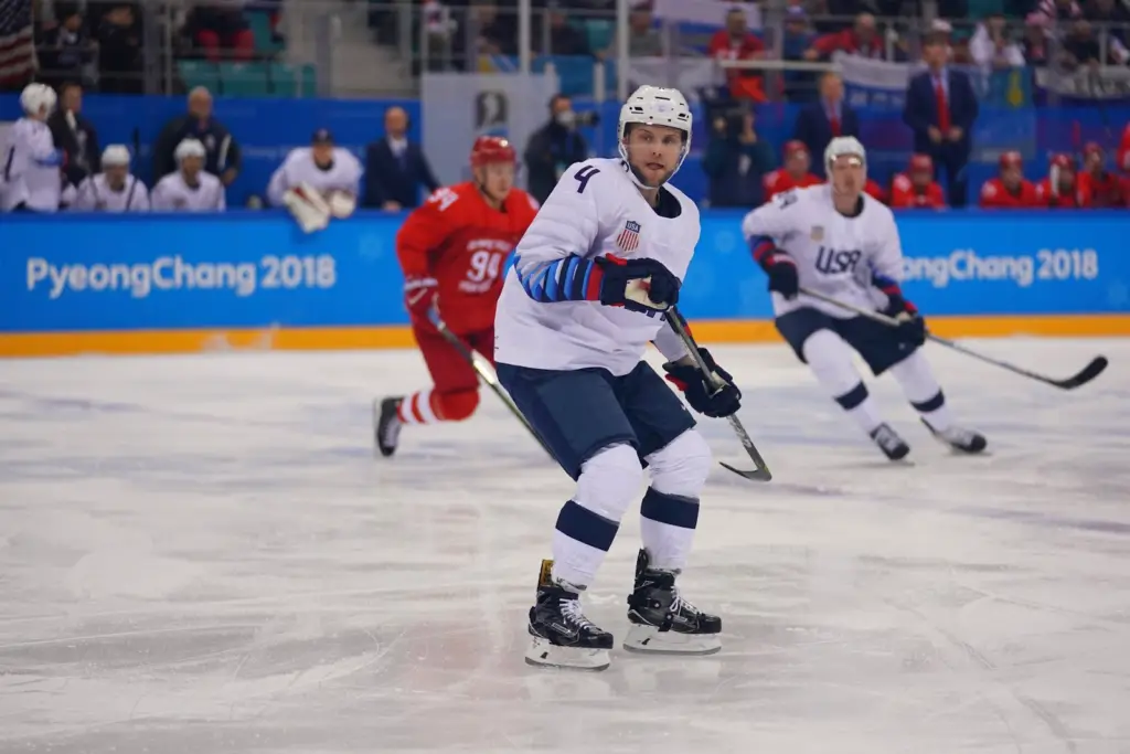 male-players-wearing-white-and-blue-uniform-playing-ice-hockey-in-a-rink-at-PyeongChang-Olympics-2018