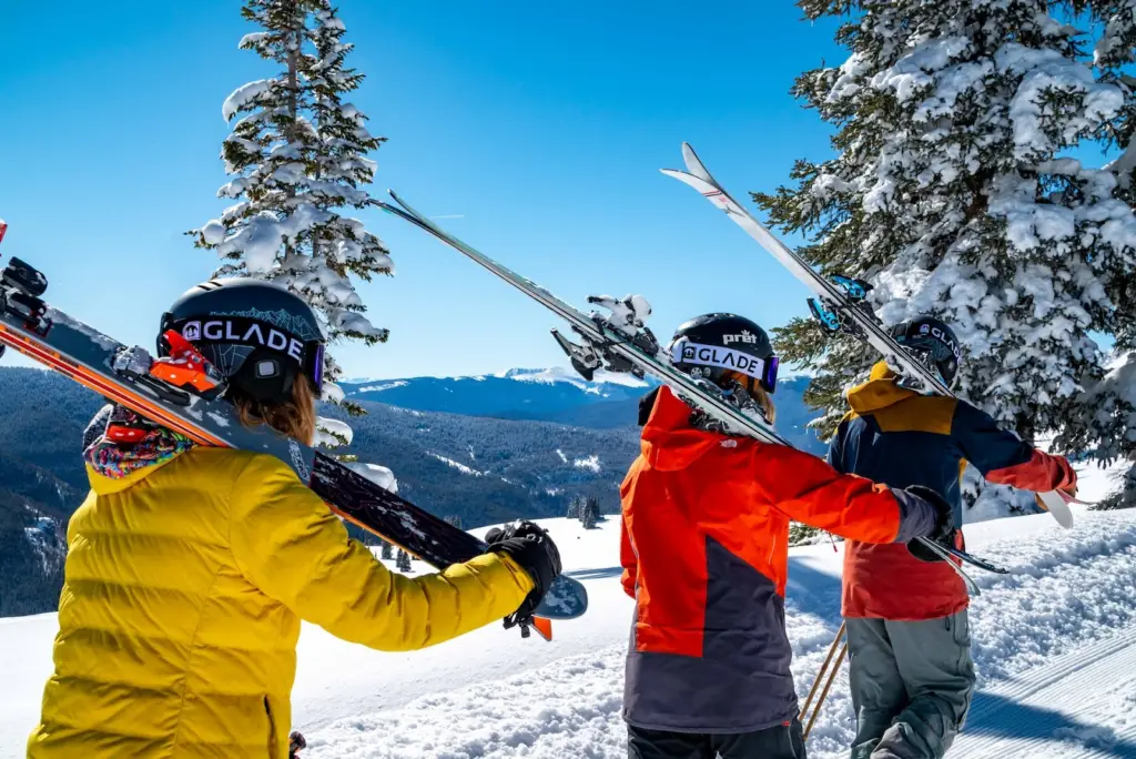 college students wearing winter sports gear bringing ski gear towards the ski hill