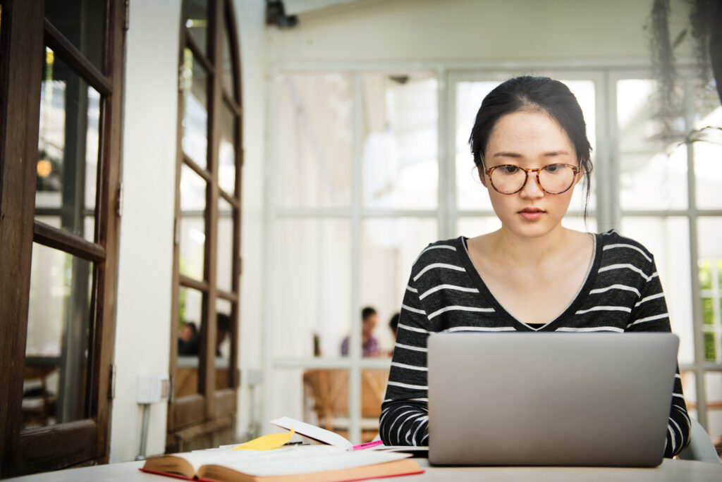 a female college student reading and using online study tools on her laptop