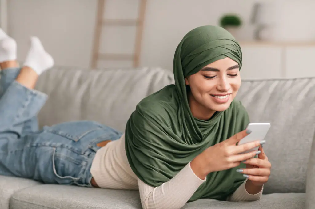 a female college student wearing hijab using online study tools on her cellphone