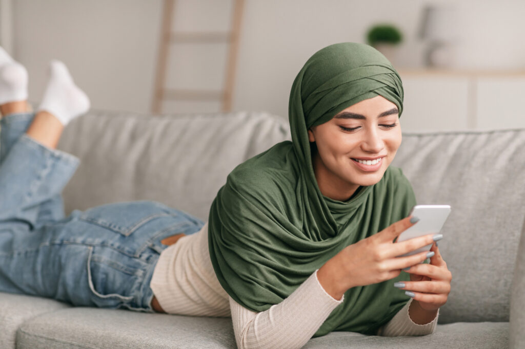 a female college student wearing hijab using online study tools on her cellphone