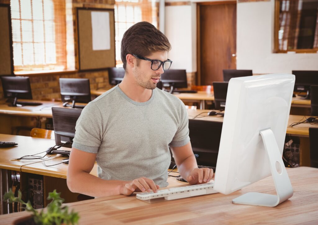 A male college student types his reorganized notes on the library computer 