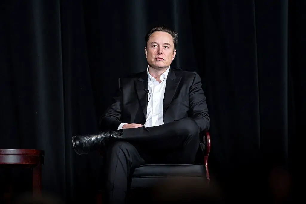 Elon Musk wearing a suit while seated on a chair onstage during the Ira C. Eaker Distinguished Speaker Presentation in the Academy's Arnold Hall on April 7, 2022 in Colorado Springs, Colorado
