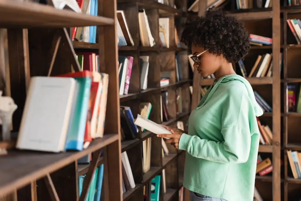 a female college student working as library assistant to save college tuition is browsing books