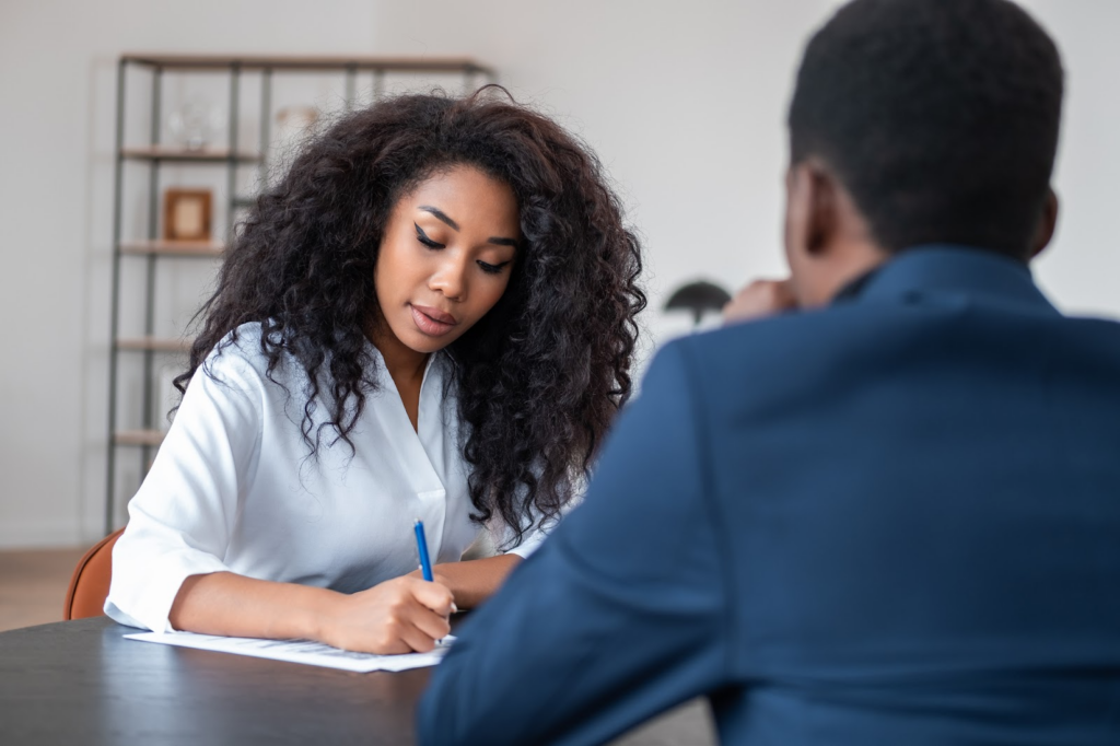 a female student writing notes during a discussion about applying to a free college with a counselor