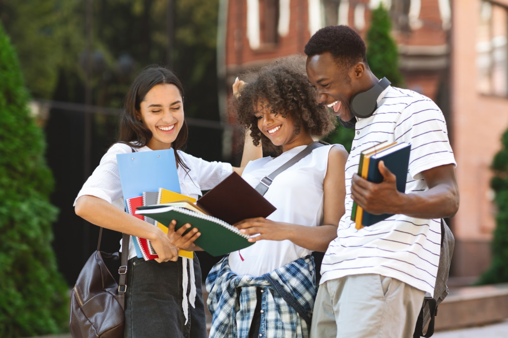 a group of male and female college students happily reading a book outdoors