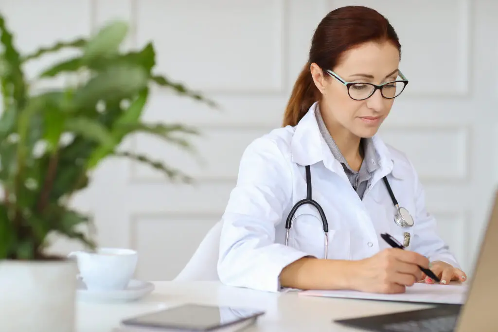 A mature female Caucasian doctor studying and writing down her notes for a patient diagnosis 