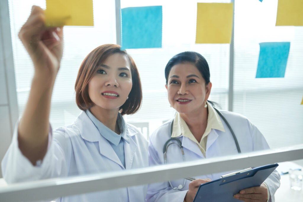 Two Asian female medical students review their findings on post-it notes after clinical rotations for an upcoming exam