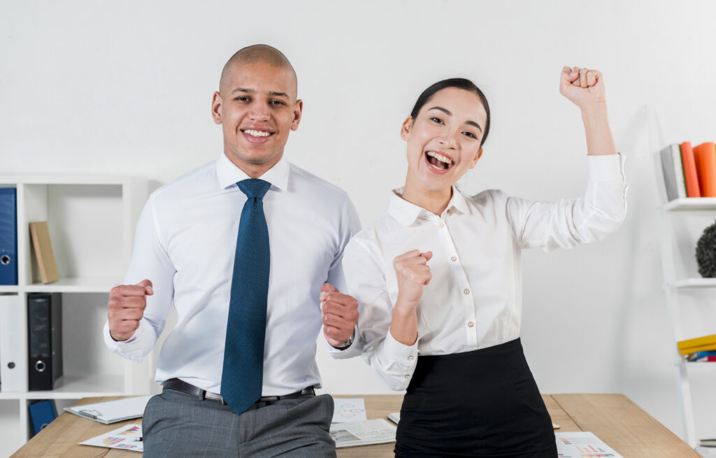 Two cheerful fresh college graduates and new office workers smiling after figuring out how to solve a challenge
