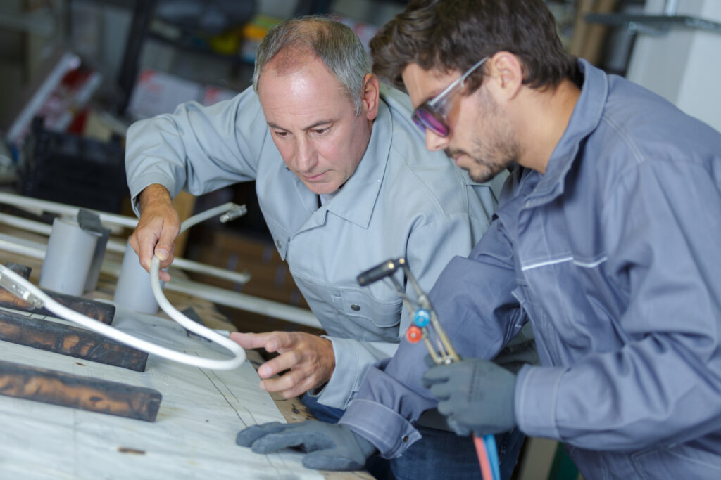 a male college student with instructor learning how to properly weld at a trade school