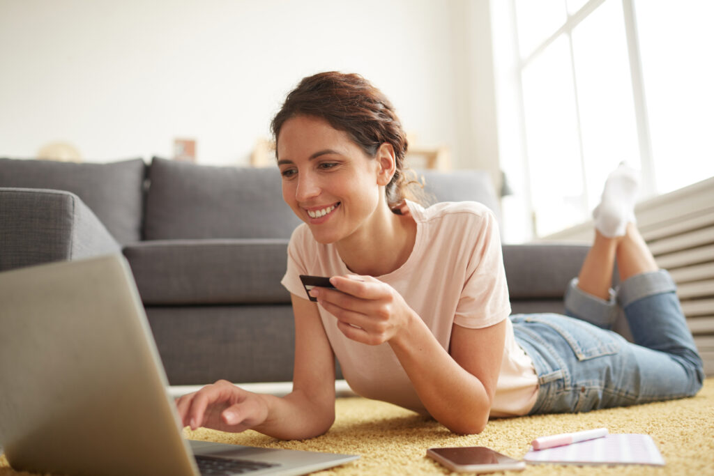 a female college student holding a bank card in front of her laptop