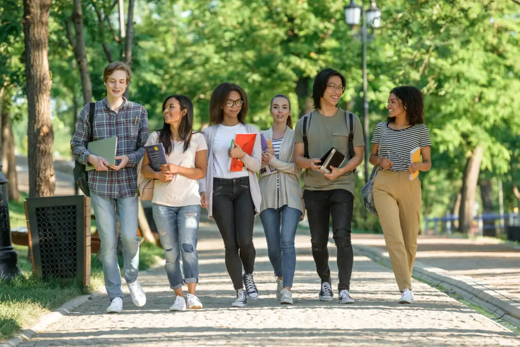 A diverse group of five college students walking to class in their college without application fees