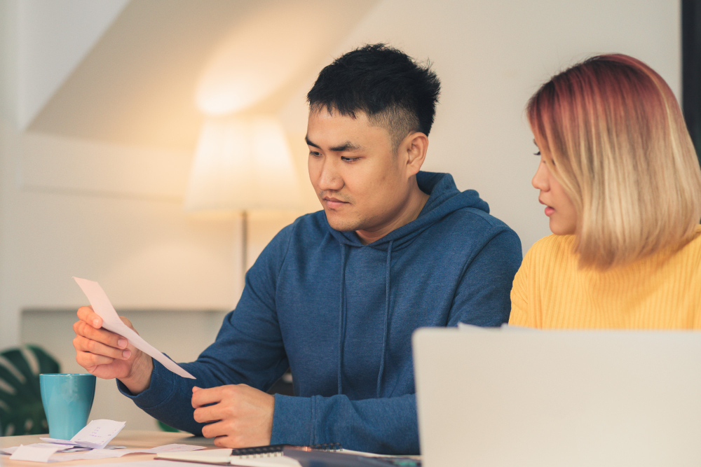 Two Asian college students and dormmates discussing and checking the shared utility and grocery costs 