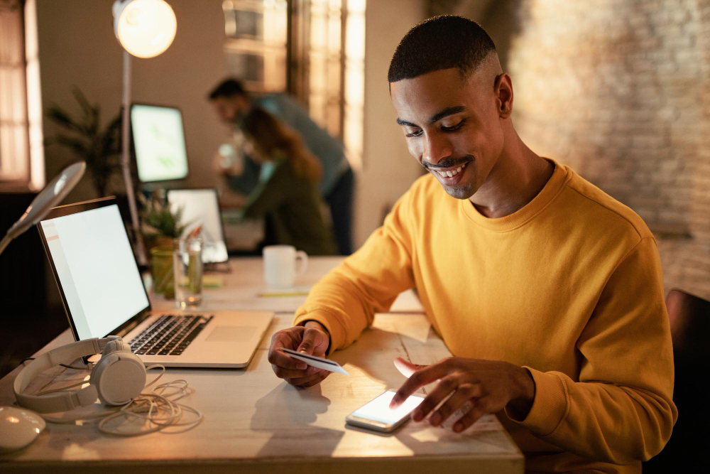 An African-American male college student happily checks his credit card balance and budget through a mobile app