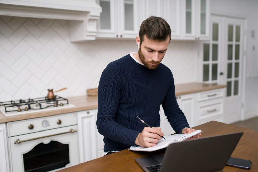 A male college student jots down his money goals and estimated monthly expenses as he's learning how to budget and save money in college