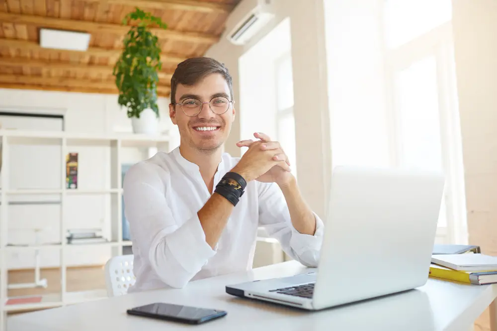 A male SEO specialist smiles as he got one of the high-paying jobs without a degree while working from home