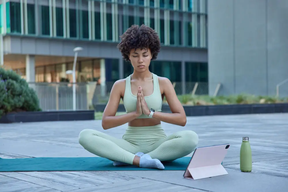 An African-American female college student practices yoga in an outdoor area
