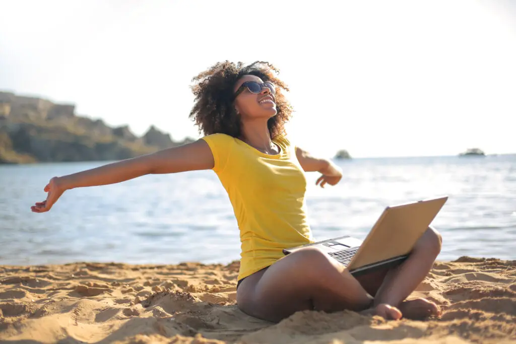 female study abroad program student sitting by the beach while studying on her laptop