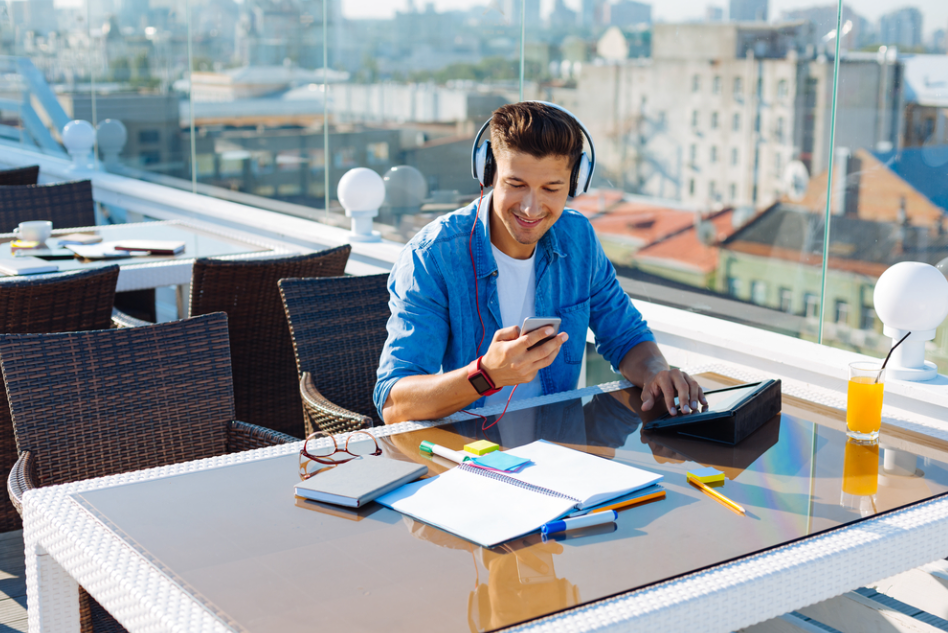 Male student listening to music outdoors as one of the ways to stay motivated while studying in college