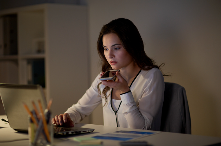 female college student using voice command recorder on a smartphone to create audio notes