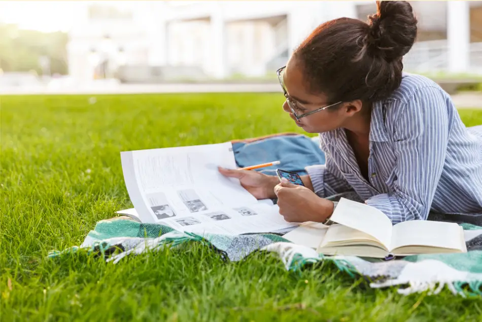 female student wearing glasses studying outdoors as one of the ways to stay motivated while studying in college