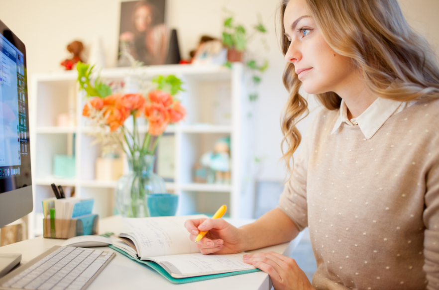 female student filling out her planner to organize her schedule and tasks  as one of the ways to stay motivated while studying in college