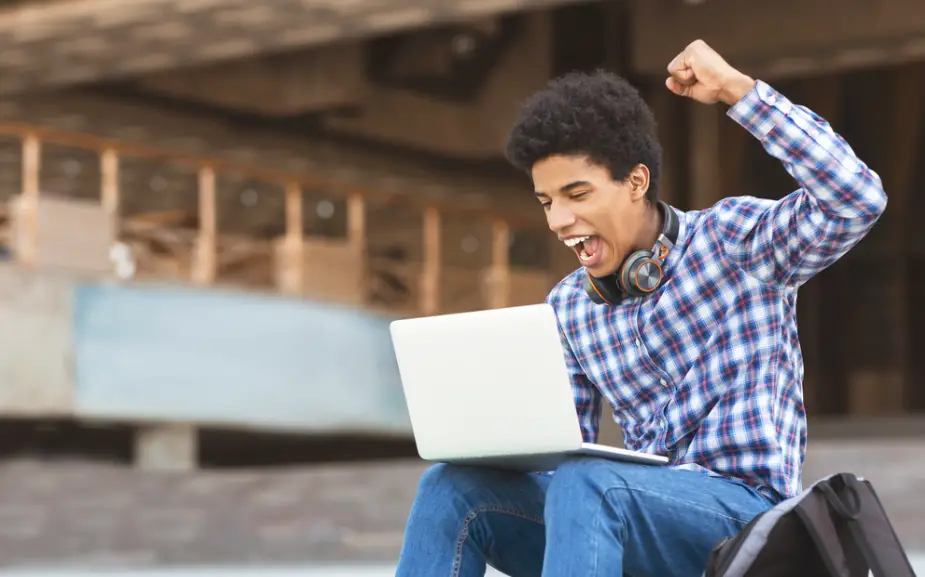 male college student with headphones on his neck looking for ways to stay motivated while studying in college