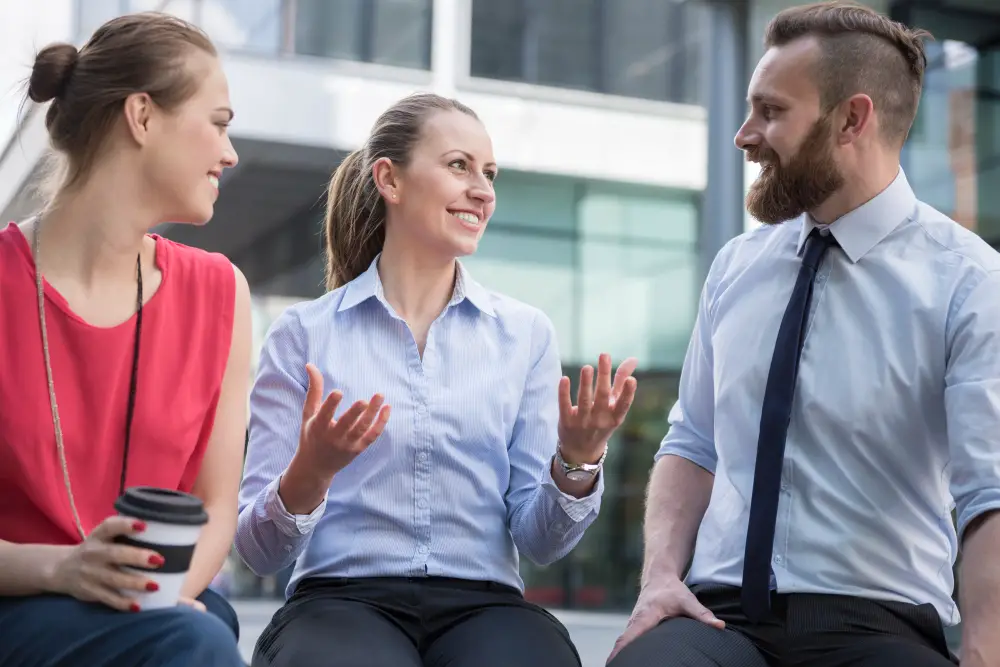 A smiling female professional engages in a discussion with two other colleagues
