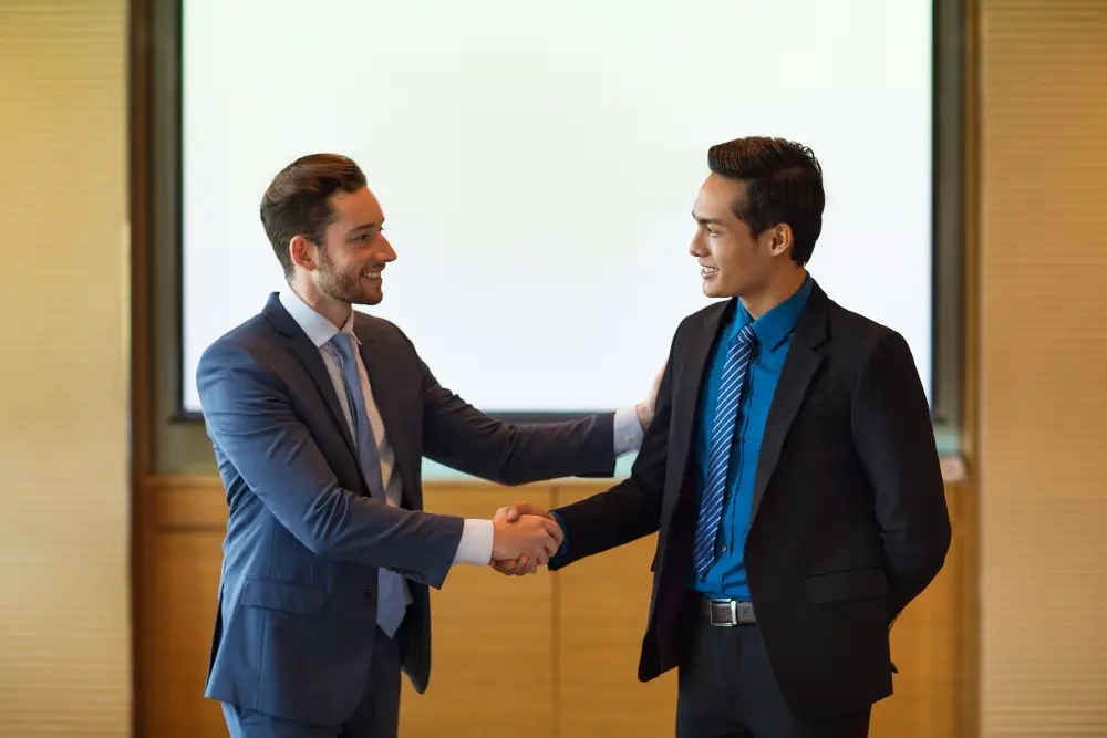 A confident male applicant shakes a hand with a smiling male recruiter after their initial messages on LinkedIn