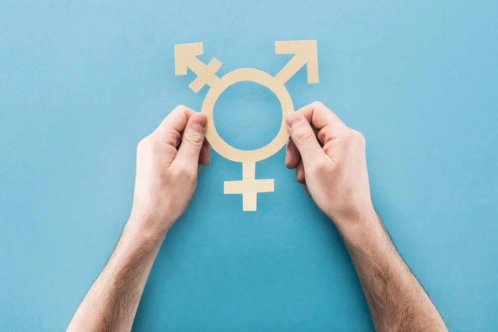 close-up-of-hands-holding-white-paper-gender-sign-against-blue-background